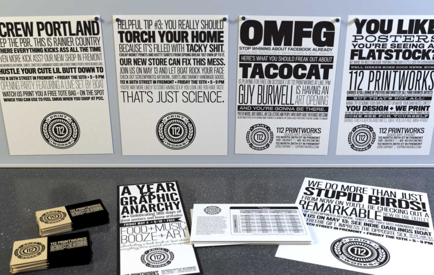 112 PrintWorks fliers pinned on wall plus table with business cards