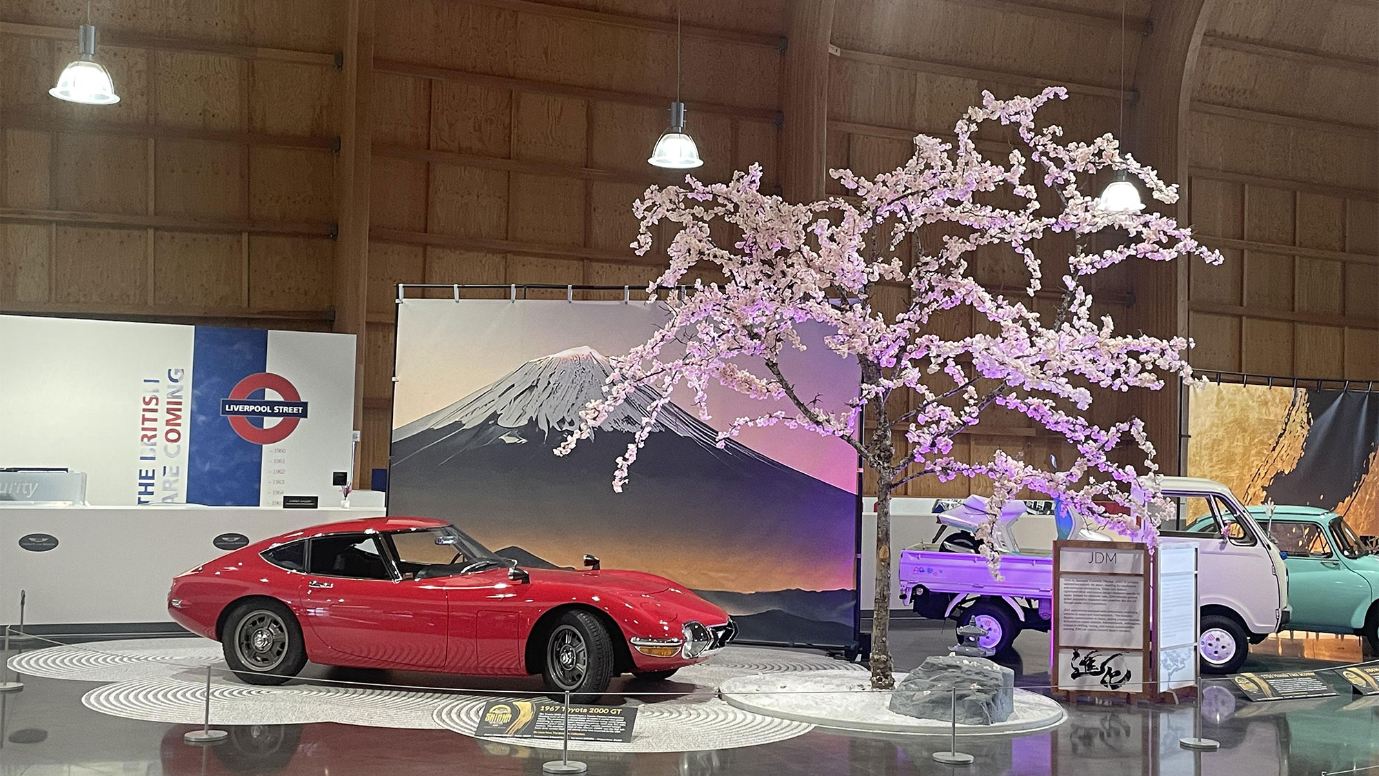 JDM environment at LeMay: Toyota 2000GT with Mt. Fuji backdrop and cherry blossom tree